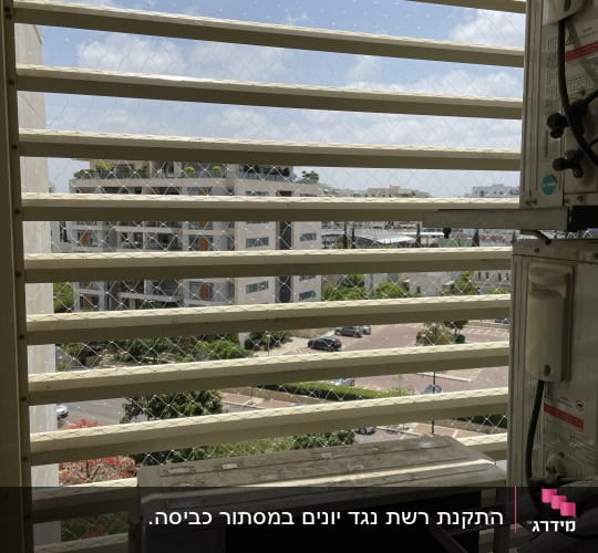 רשת נגד יונים מותקנת על חלון עם תריסים